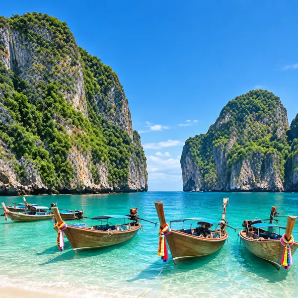 Long-tail boats below limestone cliffs in Thailand
