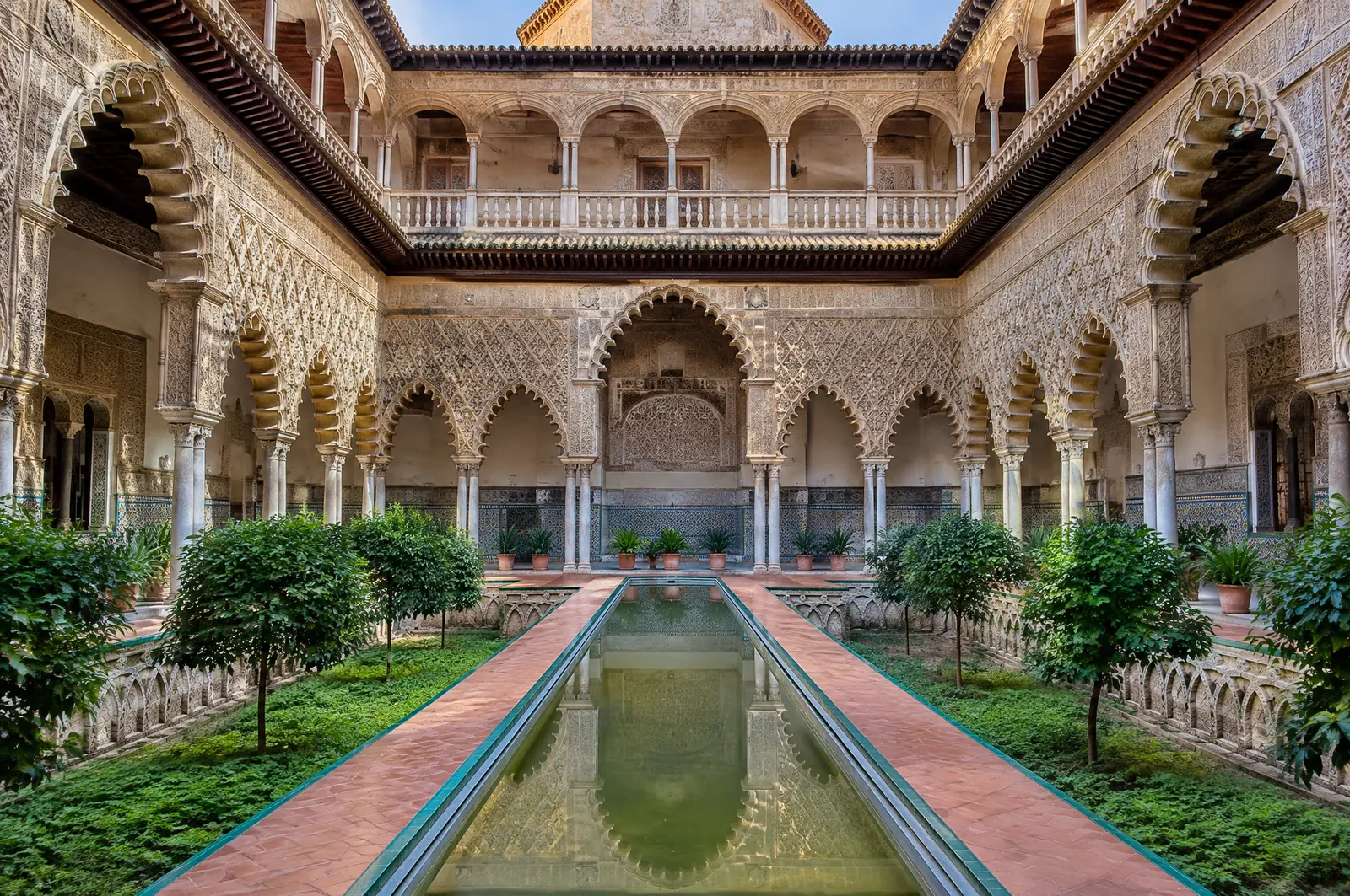 Patio de las Doncellas in the Real Alcázar, a long sunken pool between orange trees and carved Moorish arches