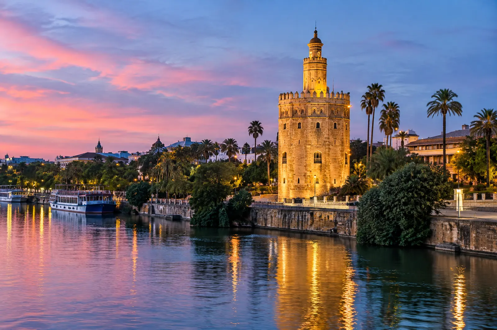 The Torre del Oro lit up on the Guadalquivir riverbank at dusk